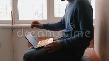 在<strong>笔记</strong>本电脑上工作。 无法辨认的年轻人打开<strong>笔记</strong>本电脑，在靠近窗户的阳台上打字。